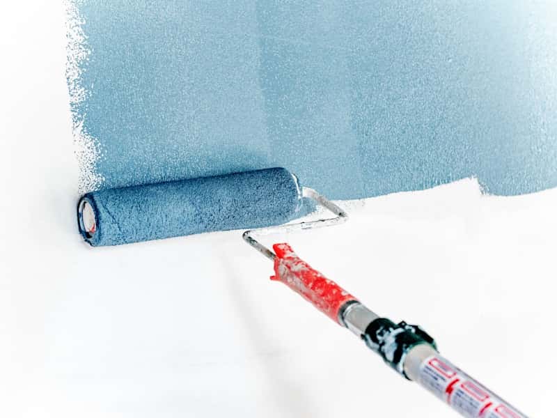 Pintor profesional de Vega Home pintando con rodillo en una vivienda de Sevilla con muebles protegidos